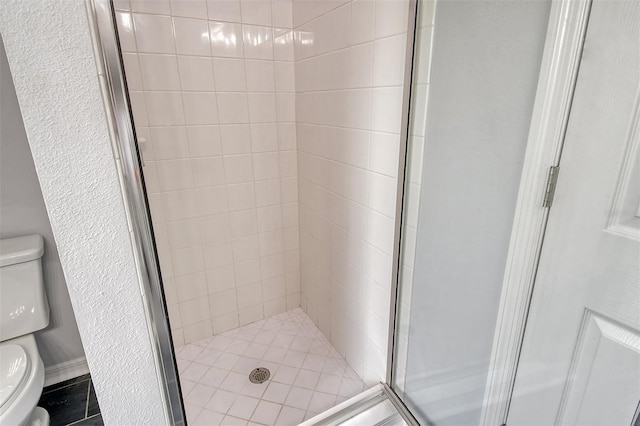 bathroom with a shower with door and toilet