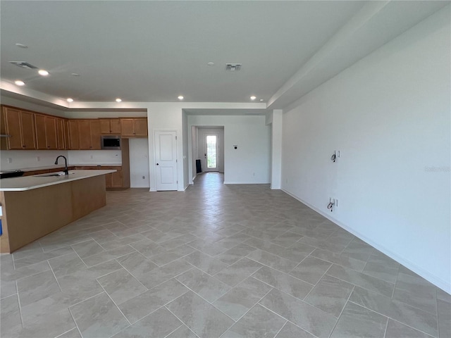 766 Hillshire Pl, Spring Hill, FL 34609 - kitchen featuring stainless steel microwave, open floor plan, recessed lighting, an island with sink, and light countertops