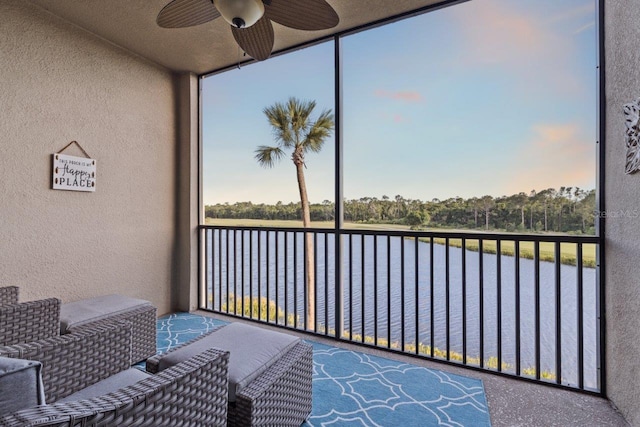 sunroom featuring ceiling fan and a water view