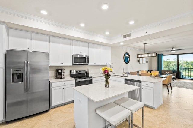 kitchen with white cabinets, sink, decorative light fixtures, appliances with stainless steel finishes, and a center island