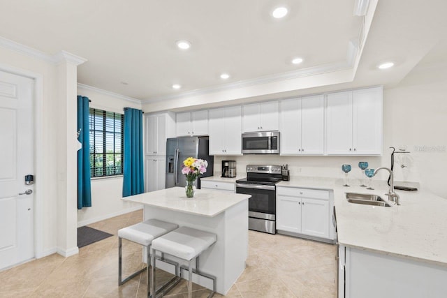 kitchen with light stone counters, sink, white cabinetry, stainless steel appliances, and a kitchen breakfast bar