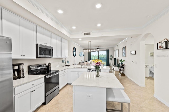 kitchen featuring a kitchen island, stainless steel appliances, kitchen peninsula, ornamental molding, and white cabinets