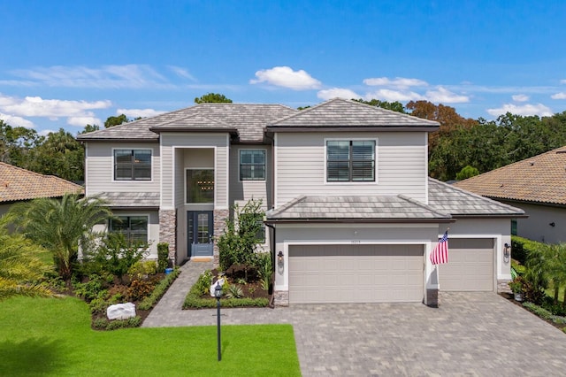 16215 Tradewind Ter, Lakewood Ranch, FL 34211 - view of front of home featuring stone siding, decorative driveway, a front lawn, and an attached garage