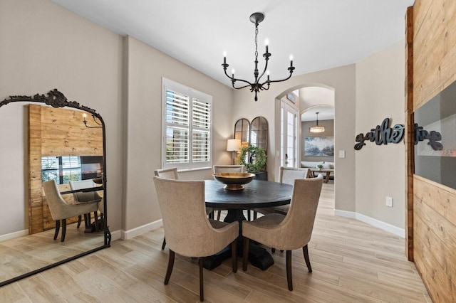 dining room featuring a healthy amount of sunlight, a chandelier, and light wood-type flooring