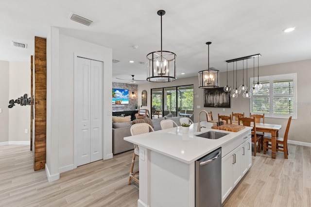 16215 Tradewind Ter, Lakewood Ranch, FL 34211 - kitchen featuring a sink, a chandelier, white cabinetry, light wood finished floors, and baseboards