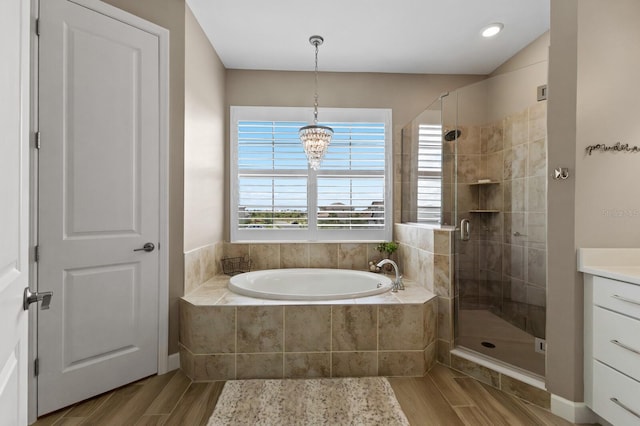 bathroom with vanity, shower with separate bathtub, hardwood / wood-style flooring, and an inviting chandelier