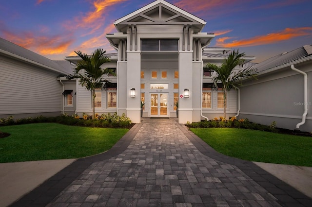 exterior entry at dusk with french doors and a lawn