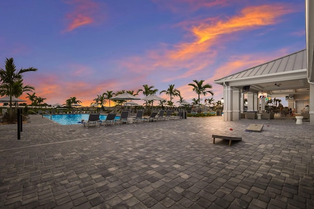 pool at dusk featuring a patio area and ceiling fan