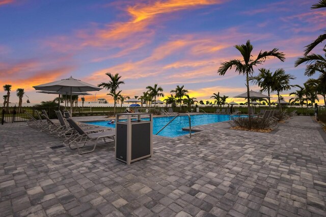 pool at dusk featuring a patio area