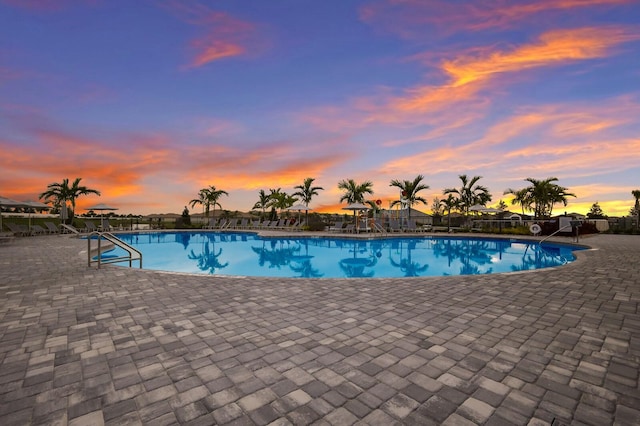 pool at dusk featuring a patio