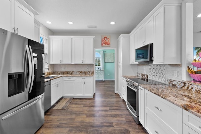 kitchen with white cabinets, backsplash, light stone countertops, dark hardwood / wood-style flooring, and stainless steel appliances