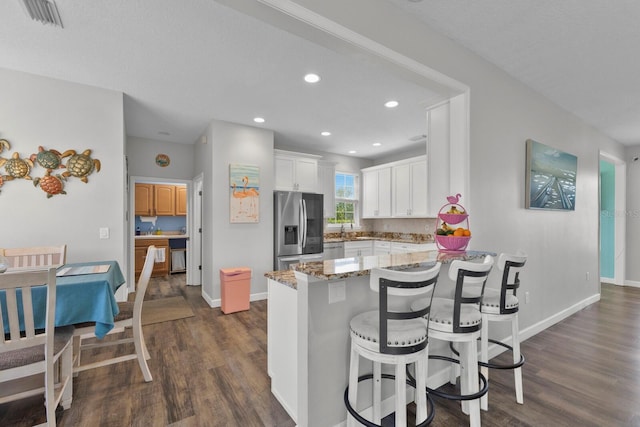 kitchen featuring white cabinetry, dark wood-type flooring, light stone counters, kitchen peninsula, and stainless steel refrigerator with ice dispenser