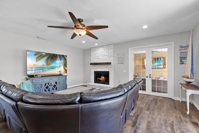 living room featuring ceiling fan, french doors, a textured ceiling, a fireplace, and dark hardwood / wood-style flooring