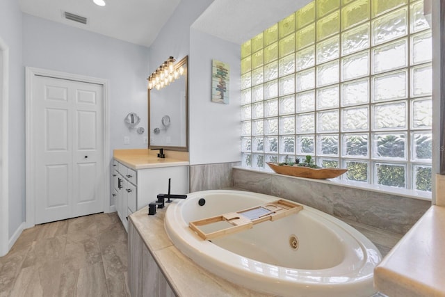 bathroom featuring tiled bath and vanity