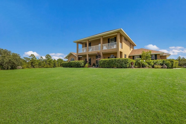 rear view of house featuring a balcony and a lawn