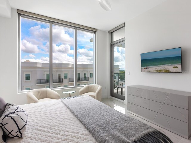 bedroom with light tile patterned flooring, a wall of windows, and access to exterior