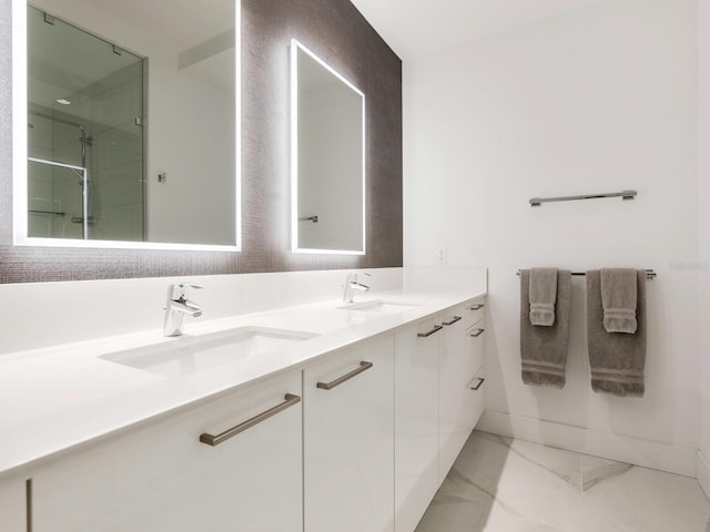 bathroom with marble finish floor, double vanity, walk in shower, and a sink