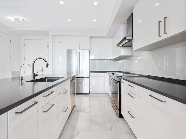 kitchen with modern cabinets, stainless steel appliances, wall chimney range hood, white cabinetry, and a sink