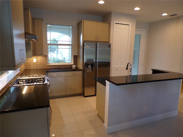 kitchen with backsplash, stainless steel appliances, light tile patterned floors, and dark stone counters