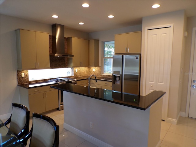 kitchen with wall chimney exhaust hood, a kitchen island with sink, stainless steel appliances, and light tile patterned flooring