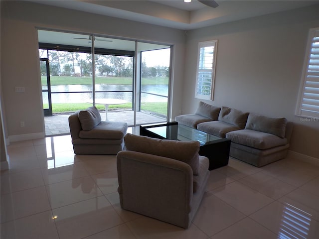 tiled living room with a water view and ceiling fan