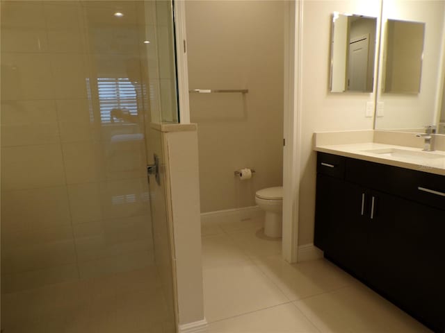 bathroom with vanity, toilet, tile patterned floors, and tiled shower