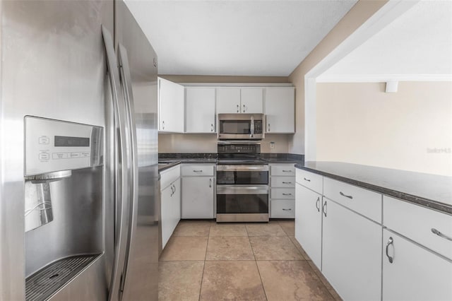 kitchen with appliances with stainless steel finishes, white cabinetry, and light tile patterned flooring