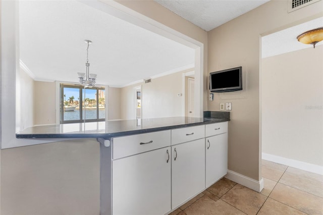 kitchen featuring crown molding, white cabinetry, a chandelier, and light tile patterned floors