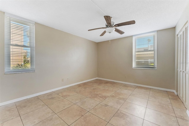 spare room featuring ceiling fan, a textured ceiling, light tile patterned floors, and plenty of natural light