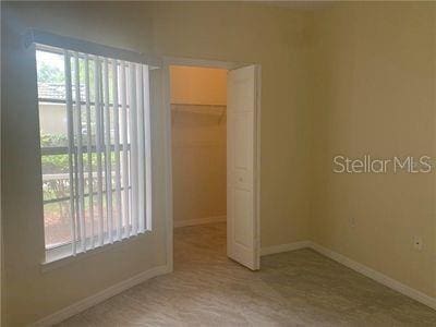 unfurnished bedroom featuring a closet, multiple windows, and a walk in closet