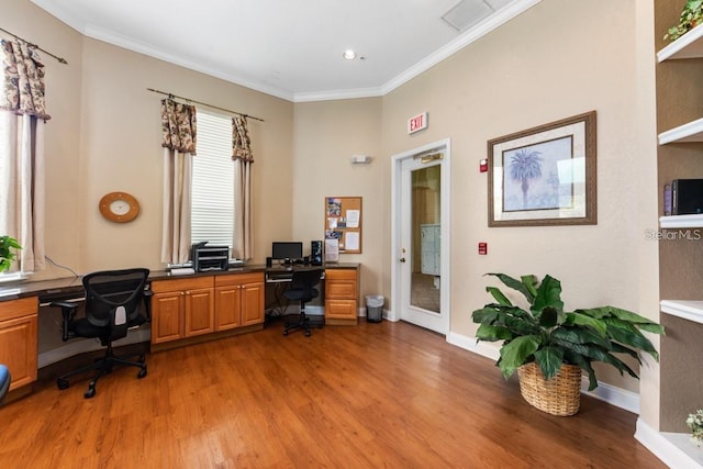 home office with built in desk, ornamental molding, and hardwood / wood-style flooring