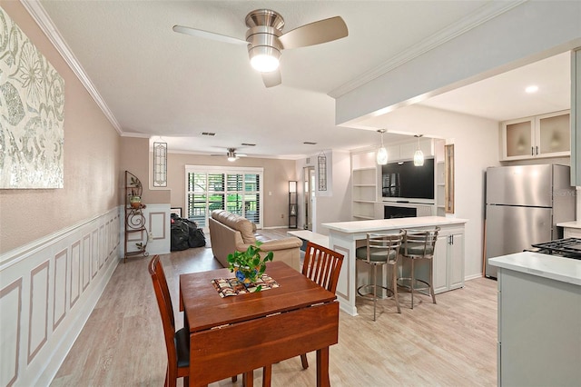 dining space featuring ceiling fan, light wood-type flooring, and ornamental molding