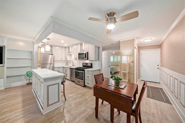 kitchen with built in shelves, stainless steel appliances, sink, a kitchen island, and hanging light fixtures