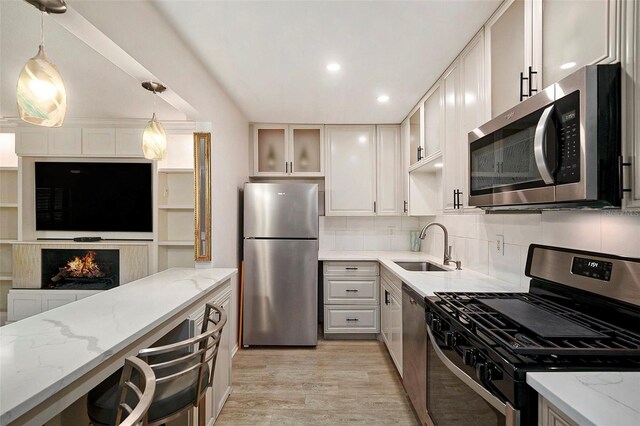 kitchen with light stone countertops, stainless steel appliances, white cabinets, and sink