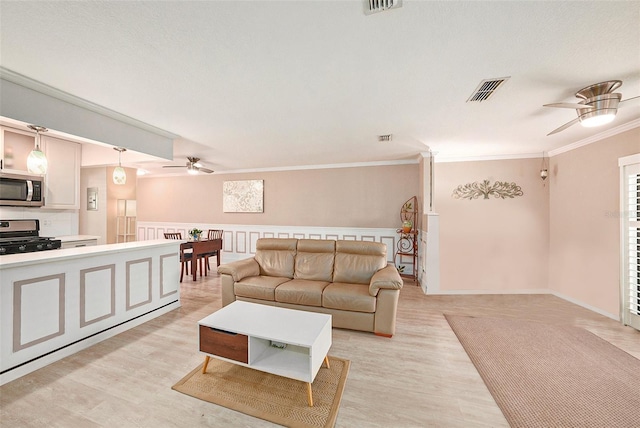 living room featuring crown molding, ceiling fan, and light hardwood / wood-style floors