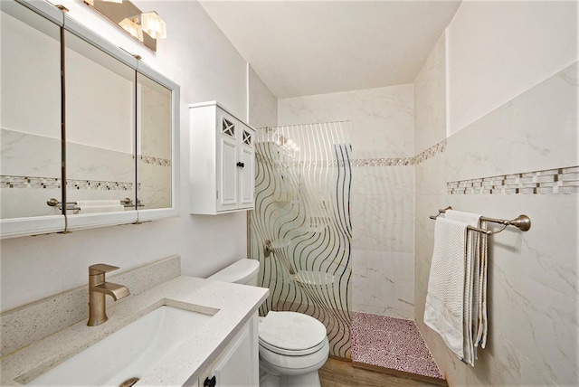 bathroom featuring vanity, toilet, and tiled shower