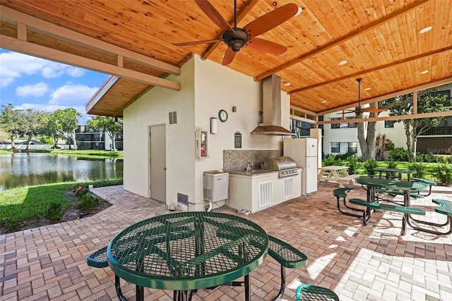 view of patio / terrace featuring ceiling fan, sink, exterior kitchen, a water view, and grilling area