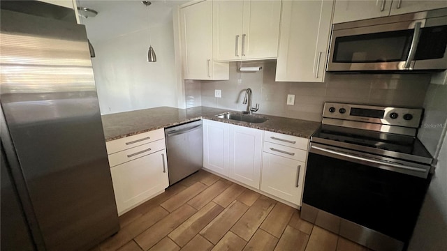 kitchen featuring stone counters, appliances with stainless steel finishes, sink, light wood-type flooring, and white cabinets