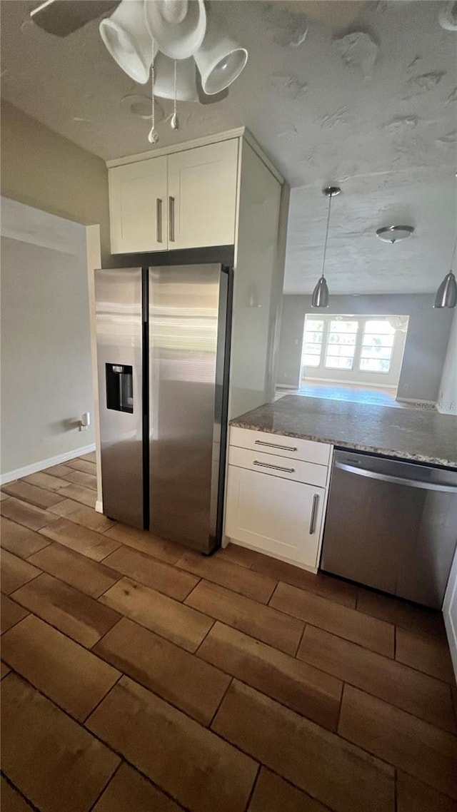 kitchen with dark wood-type flooring, white cabinets, hanging light fixtures, and stainless steel appliances