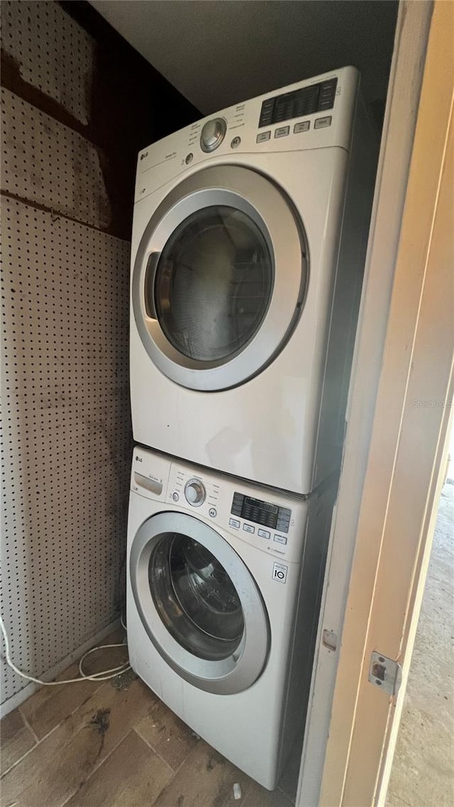 clothes washing area with stacked washing maching and dryer