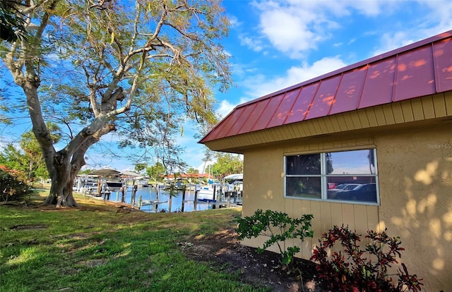 view of home's exterior featuring a lawn, a water view, and a boat dock