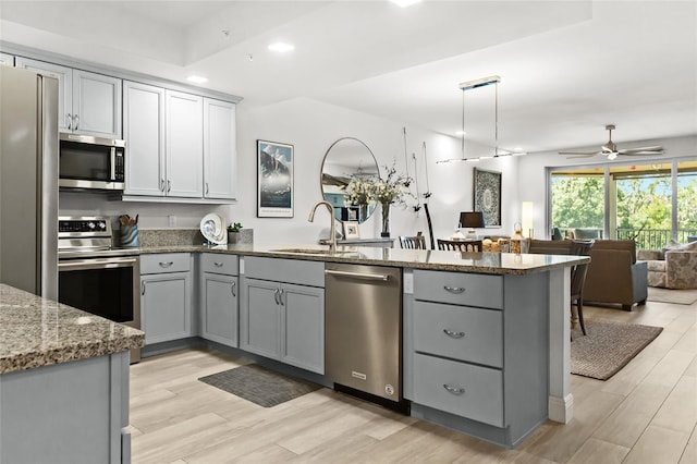 kitchen with kitchen peninsula, sink, light hardwood / wood-style floors, and appliances with stainless steel finishes