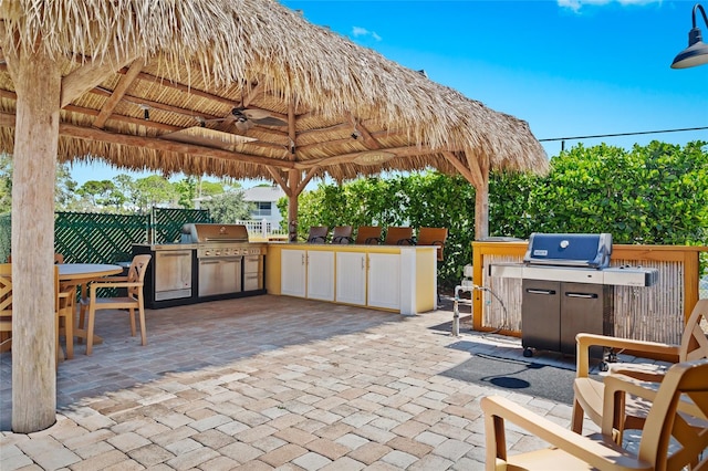 view of patio / terrace featuring a gazebo, a grill, ceiling fan, and exterior kitchen