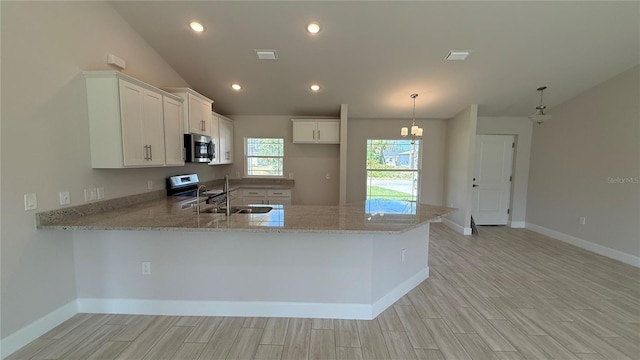 kitchen with stainless steel appliances, light stone counters, light wood finished floors, and a peninsula