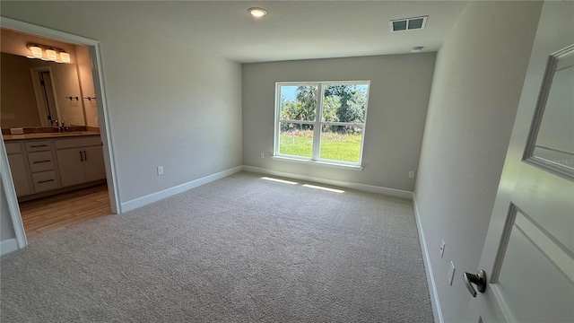 unfurnished bedroom with baseboards, visible vents, and light carpet