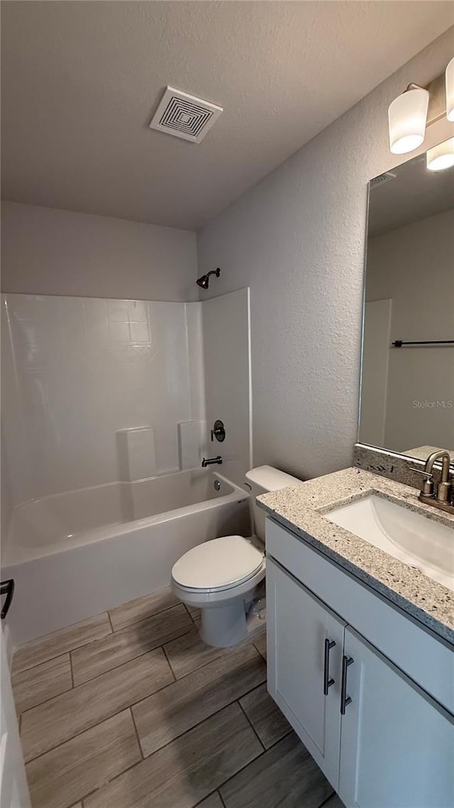 full bath featuring visible vents, wood finish floors, vanity, toilet, and shower / bathtub combination