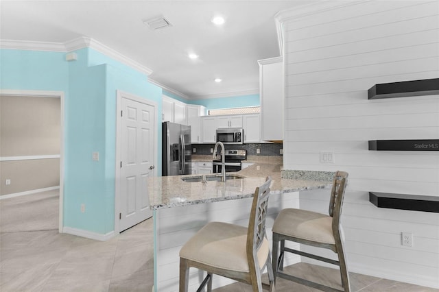 kitchen with white cabinets, a breakfast bar, kitchen peninsula, stainless steel appliances, and sink