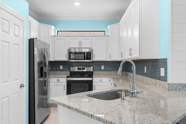 kitchen with light stone counters, stainless steel appliances, sink, and white cabinetry