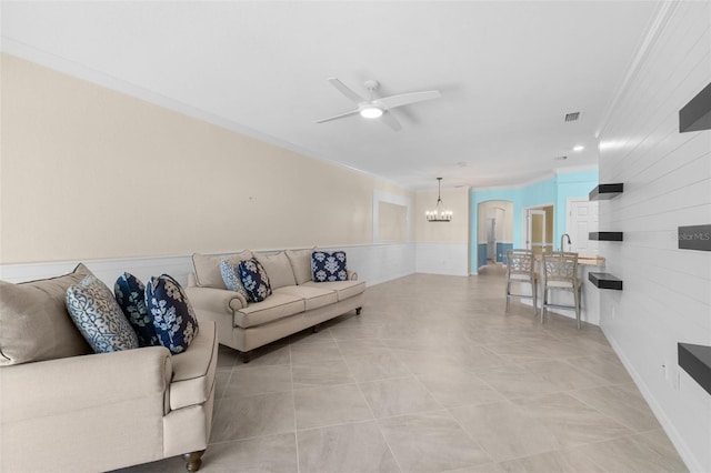 tiled living room featuring ceiling fan with notable chandelier and ornamental molding