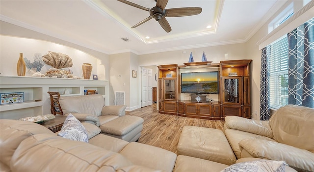 living room with crown molding, light hardwood / wood-style floors, a tray ceiling, and ceiling fan